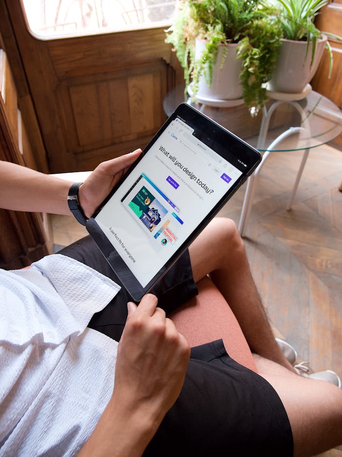 A young man sitting indoors using a tablet, engaged in digital content.